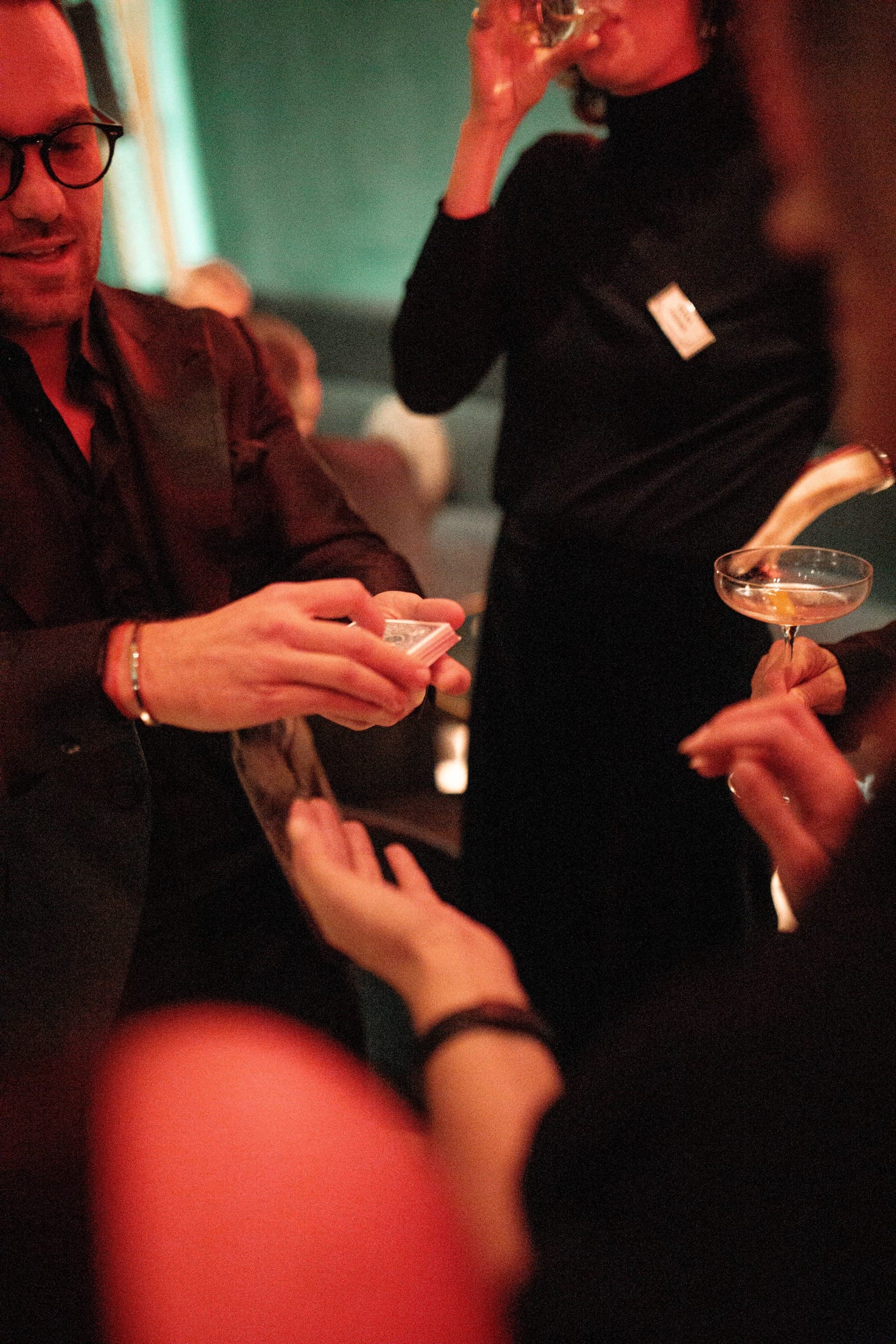 Matteo cutting the deck between guests, a coupe glass catching the light.